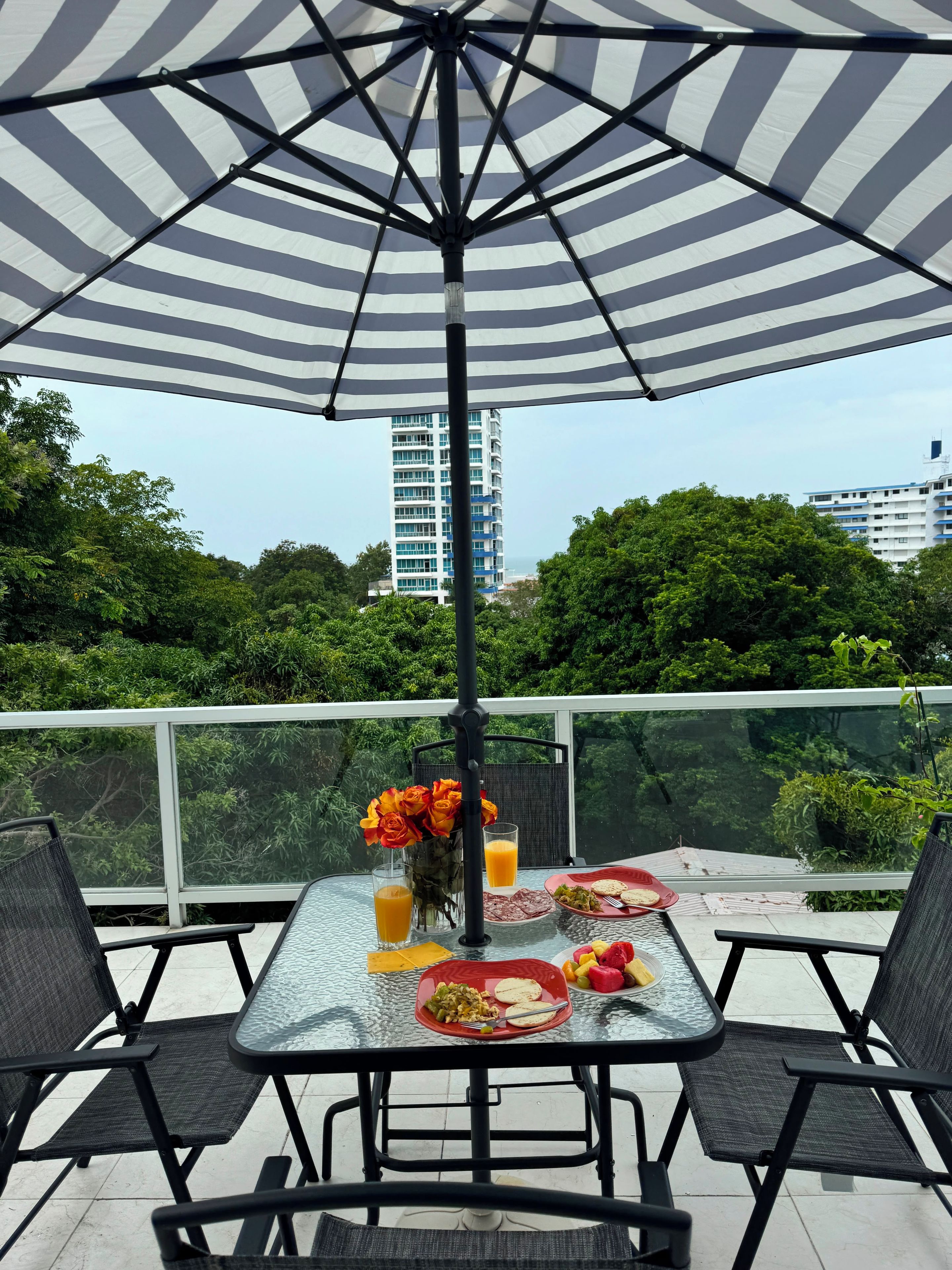 An outdoor dining area with a table, chairs, and a striped umbrella.