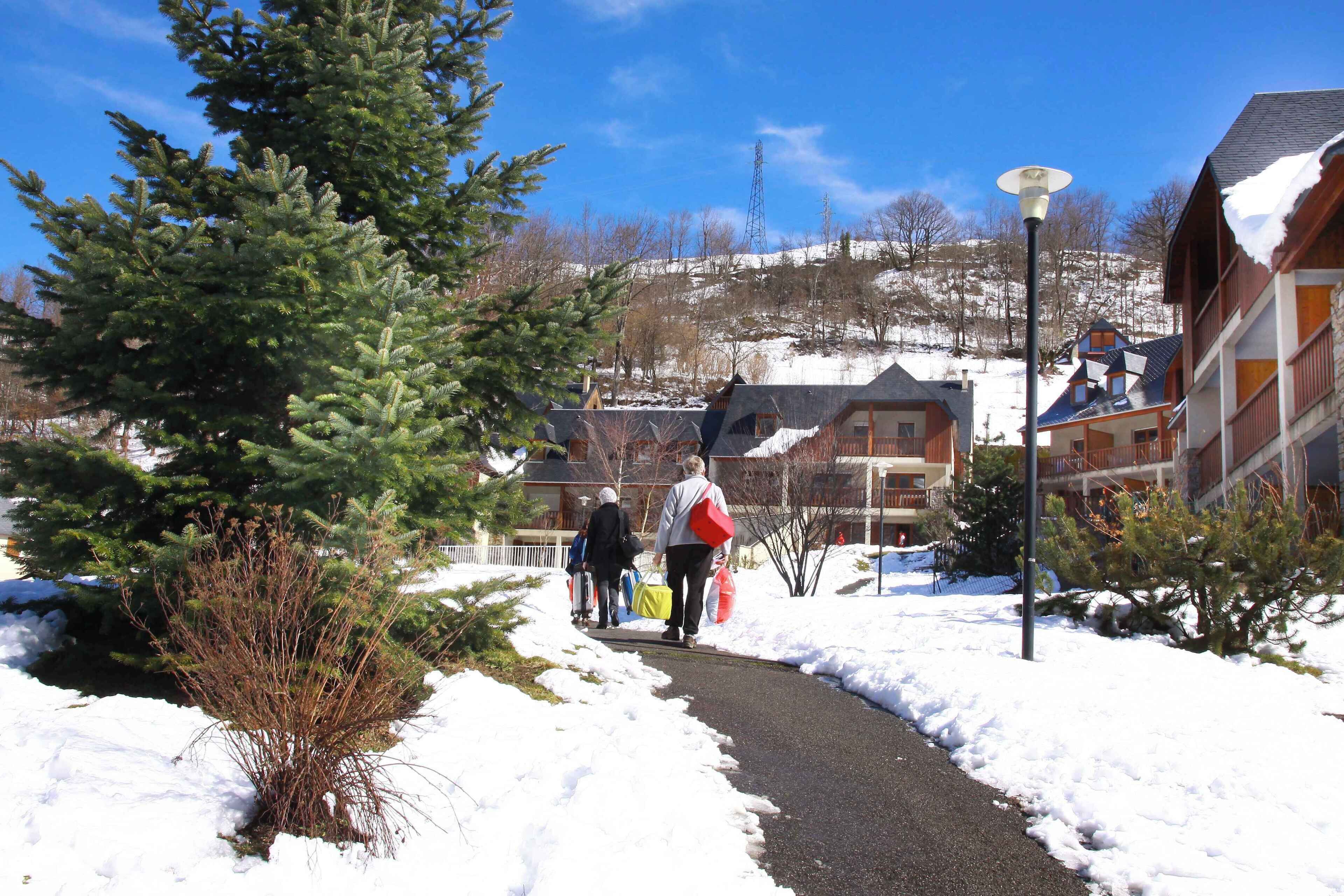 A snow-covered path leading to buildings with a clear sky.