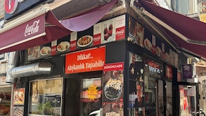 A street food stall with a Coca-Cola sign, food menu, and people dining outside. - Taksim Square - Deluxe Studio 302 (Istanbul)