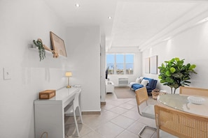 Ein modernes Wohnzimmer mit Essbereich, weißen Wänden und Meerblick.