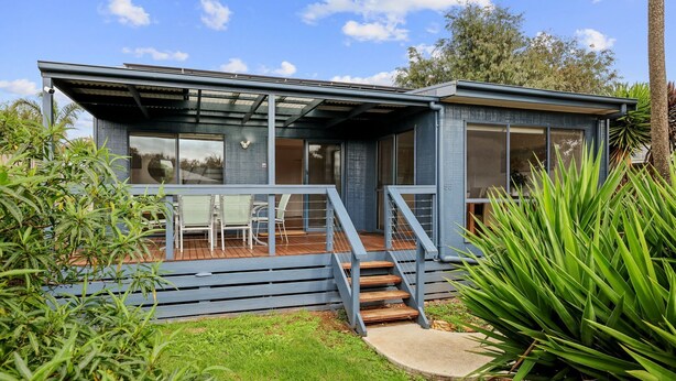 Een modern huis met een overdekt terras, grote ramen en het nummer '55' aan de zijkant.