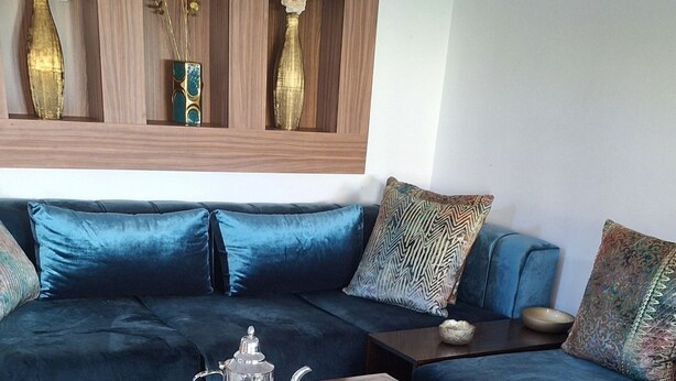 A dining table set with breakfast items, a sofa, and decorative vases in the background.