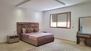 A bedroom with a bed, bedside tables, a dresser, a mirror, and a window with blinds.