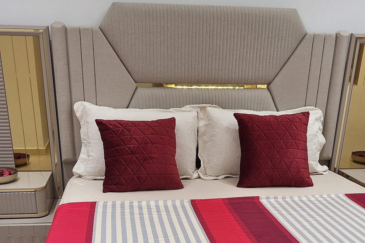 Una cama con colcha a rayas, dos almohadas y cabecero.