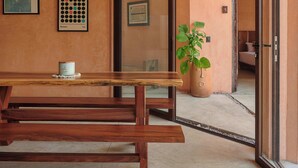 A room with a wooden bench, a potted plant, and framed artwork on the wall. - Casa Tintorera (Santa María Colotepec)