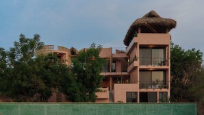 A multi-story building with a thatched roof, balconies, and large windows. - Casa Tintorera (Santa María Colotepec)