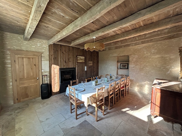 A rustic dining room with a long table set for a meal, wooden walls, and a fireplace.