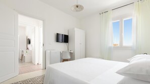 Una camera da letto con un letto, una TV a muro, un armadio e una finestra con tende.
