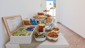 Un tavolo da buffet con diversi cibi, tra cui pasticcini, frutta secca e condimenti.