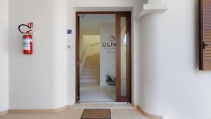 A hotel entrance with a fire extinguisher mounted on the wall, a welcome sign, and a staircase leading inside. - Ulivo di Rocco - Bilo Standard PT by BarbarHouse (Cannole)