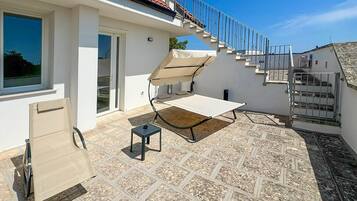 Un espace extérieur abrité comprenant une table, une chaise et une petite table sur laquelle se trouve un appareil.