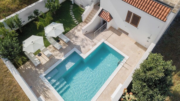 Ein zweistöckiges Haus mit Swimmingpool, Sitzgelegenheiten im Freien und einem Garten.