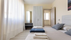 Ein Schlafzimmer mit Bett, Kleiderschrank, Spiegel und Fenster.