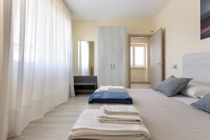 Una camera da letto con un letto, un armadio, uno specchio e una finestra.