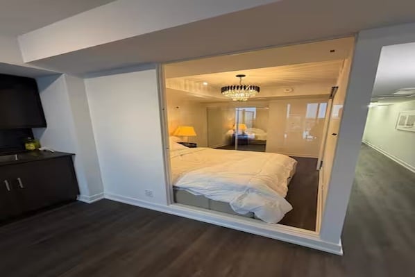 A bedroom with a bed, a chandelier, a nightstand, and a dark wooden dresser.