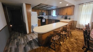 A compact kitchen with a central island, wooden bar stools, and a dining table with chairs.