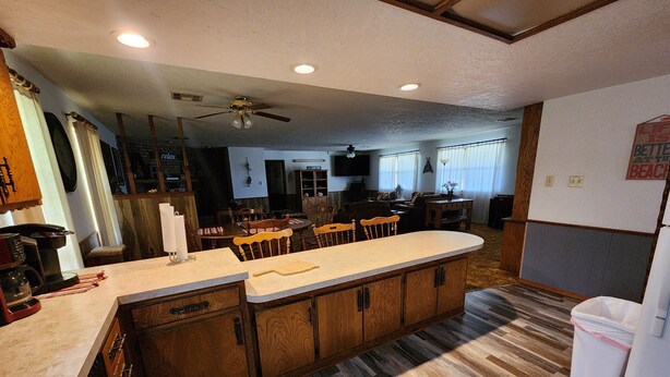 A kitchen with wooden cabinets, a central island, and a dining area with chairs and a table.