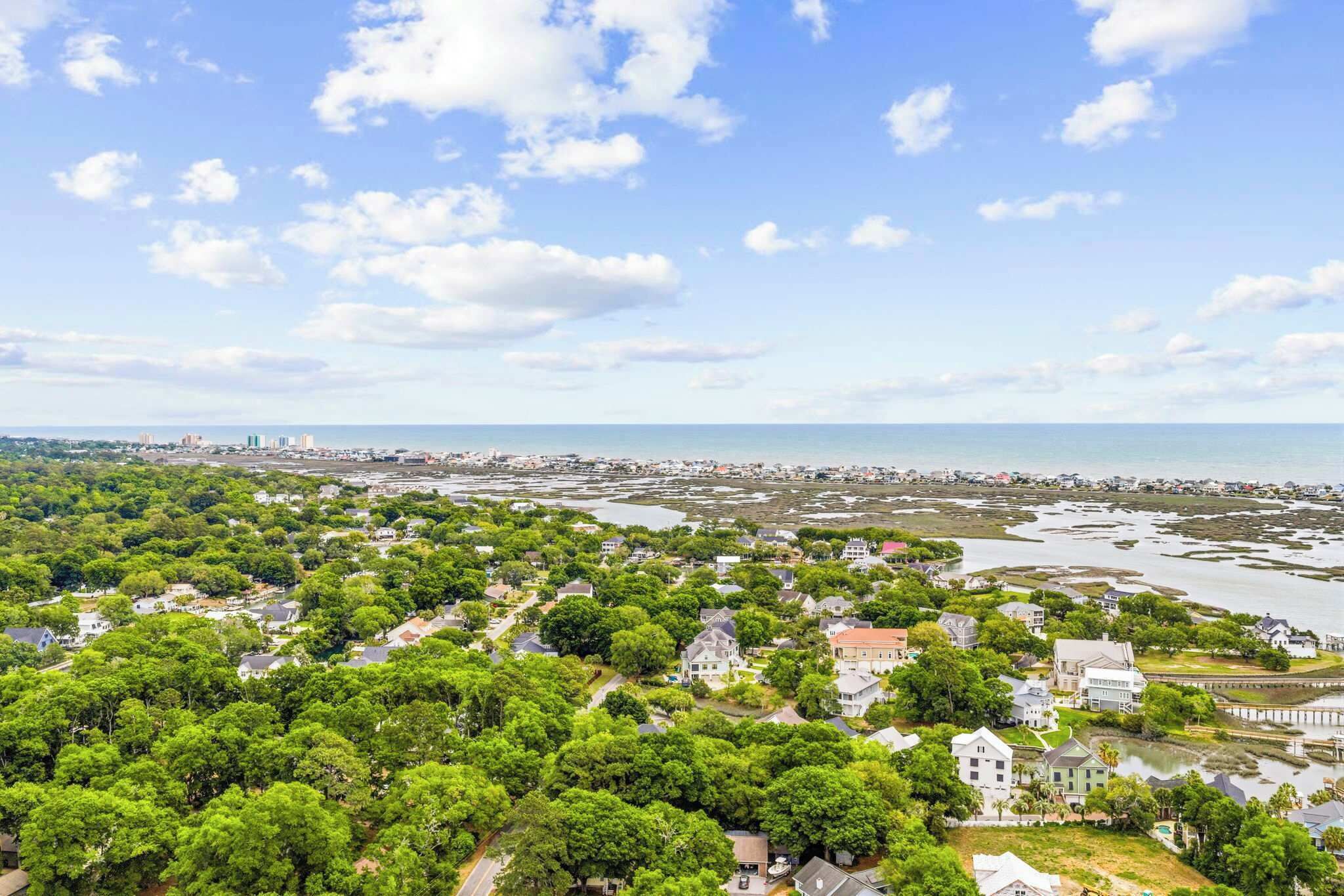 An aerial view of a coastal residential area with houses, a marina, and a clear sky.