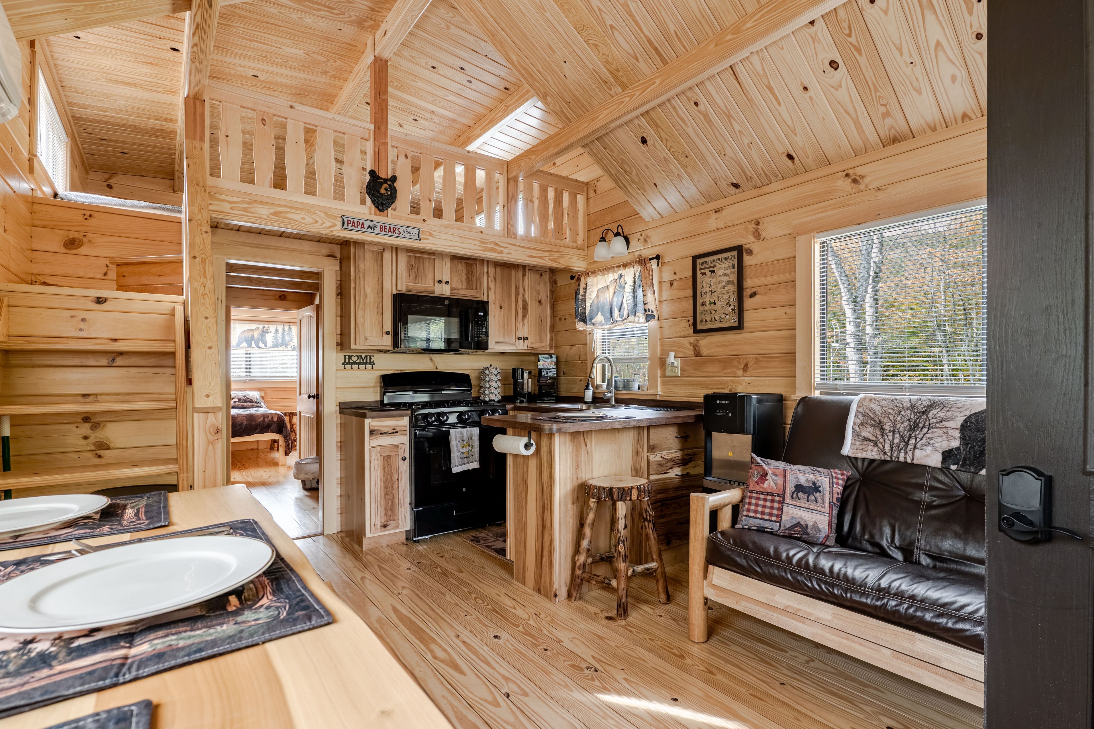 A cabin interior with a kitchen, dining area, and a cozy seating area.