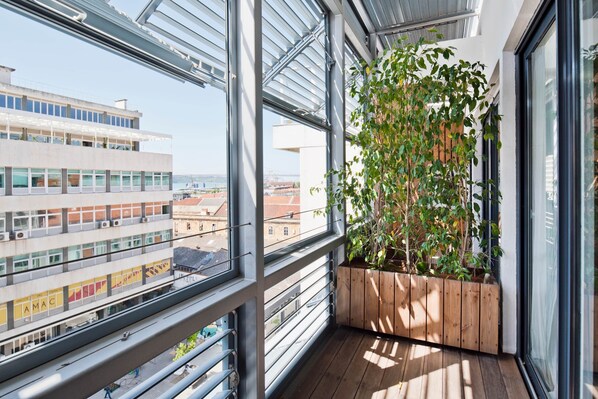 Ein Balkon mit einem Holzpflanzgefäß und Blick auf die Stadtlandschaft.