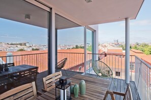 Ein Balkon mit Tisch, Stühlen und einer Hängematte, mit Blick auf eine Stadtlandschaft.