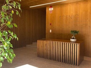 A reception desk with a wooden finish, a potted plant, and the word 'SCENIC' on the wall. - Scenic 2 - TERRACE, VIEW & SPACE (Lisbon)