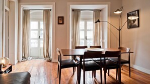 A dining area with a wooden table, chairs, a floor lamp, and curtains. - Chiado 5 -  Histórico (Lisbon)