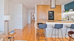 Una cocina moderna con armarios de madera, campana extractora de acero inoxidable y una zona de bar con taburetes.