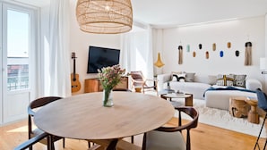 Una sala de estar moderna con una mesa redonda de madera, un sofá, un televisor y una guitarra.
