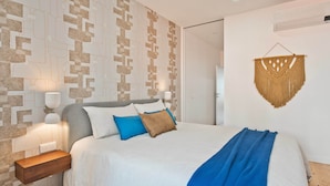 Un dormitorio con pared estampada, una cama con almohadas, una mesita de noche y un adorno en la pared.