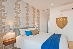 Ein Schlafzimmer mit Wandmuster, einem Bett mit Kissen, einem Nachttisch und einer Wanddekoration.