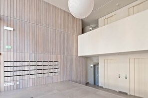 Ein modernes Interieur mit einer Wand aus Holzpaneelen, einem Fliesenboden und einer Reihe von Aufzügen.