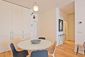 A modern kitchen with white cabinets, a round glass table, and a pendant light. - Ribeira 6 - Boavista Design and Comfort (Lisbon)