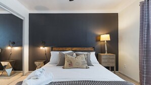 A hotel room with a bed, pillows, a bedside lamp, a nightstand, and a towel on the floor. - Austin Apartments by Andes STR (Austin)