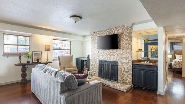A spacious living room with a sofa, a television, and a fireplace. - Austin Apartments by Andes STR (Austin)