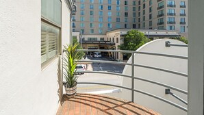 A balcony with a view of a multi-story building, a street with vehicles, and a plant. - Austin Apartments by Andes STR (Austin)