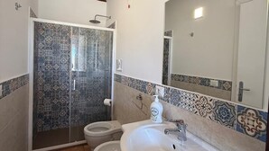 Ein Badezimmer mit Dusche, zwei Toiletten, einem Waschbecken und einem Spiegel.