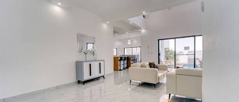 A spacious living area with a marble floor, a sofa, a cabinet, and a large window.