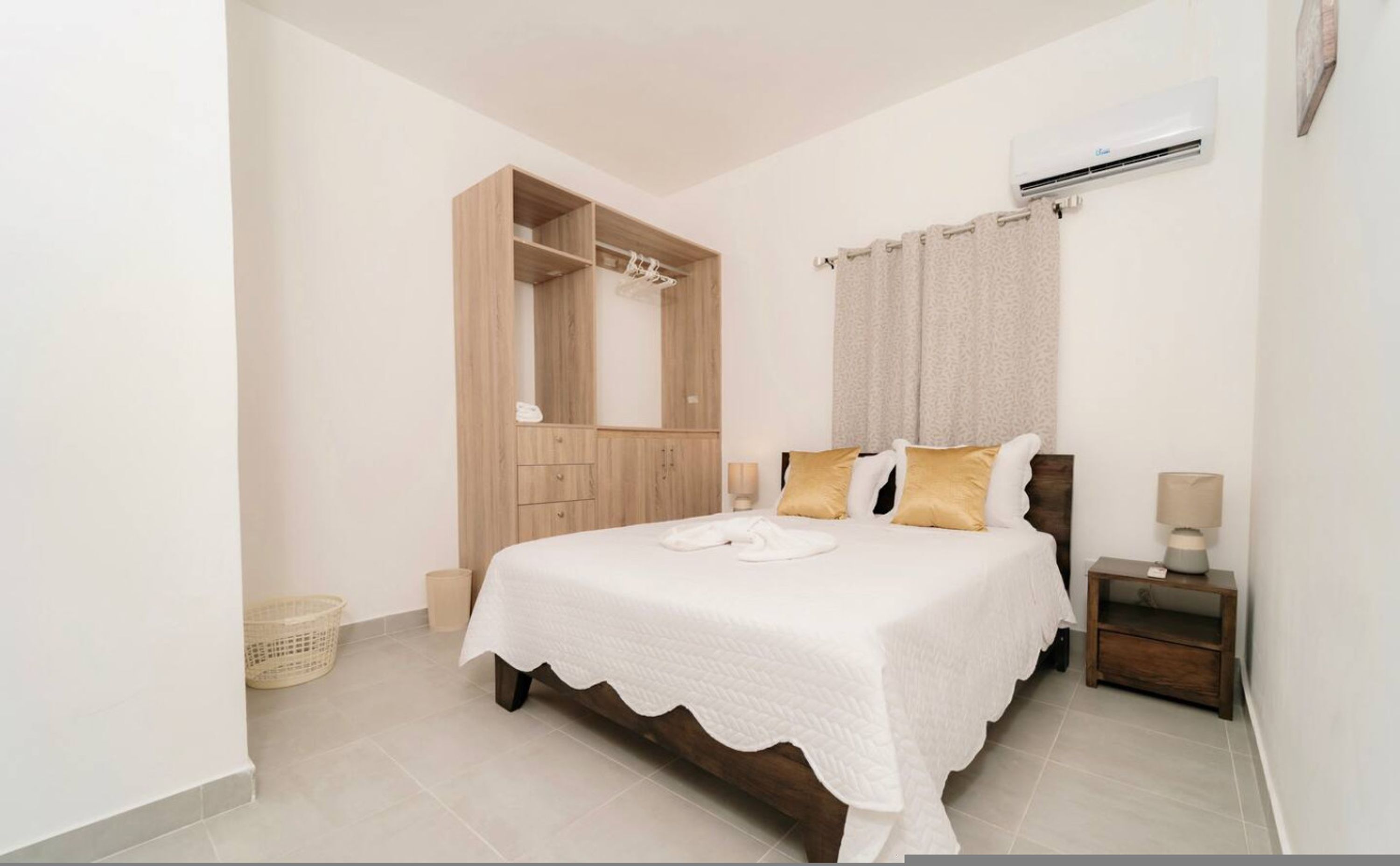 A bedroom with a bed, a wardrobe, an air conditioning unit, and a nightstand.