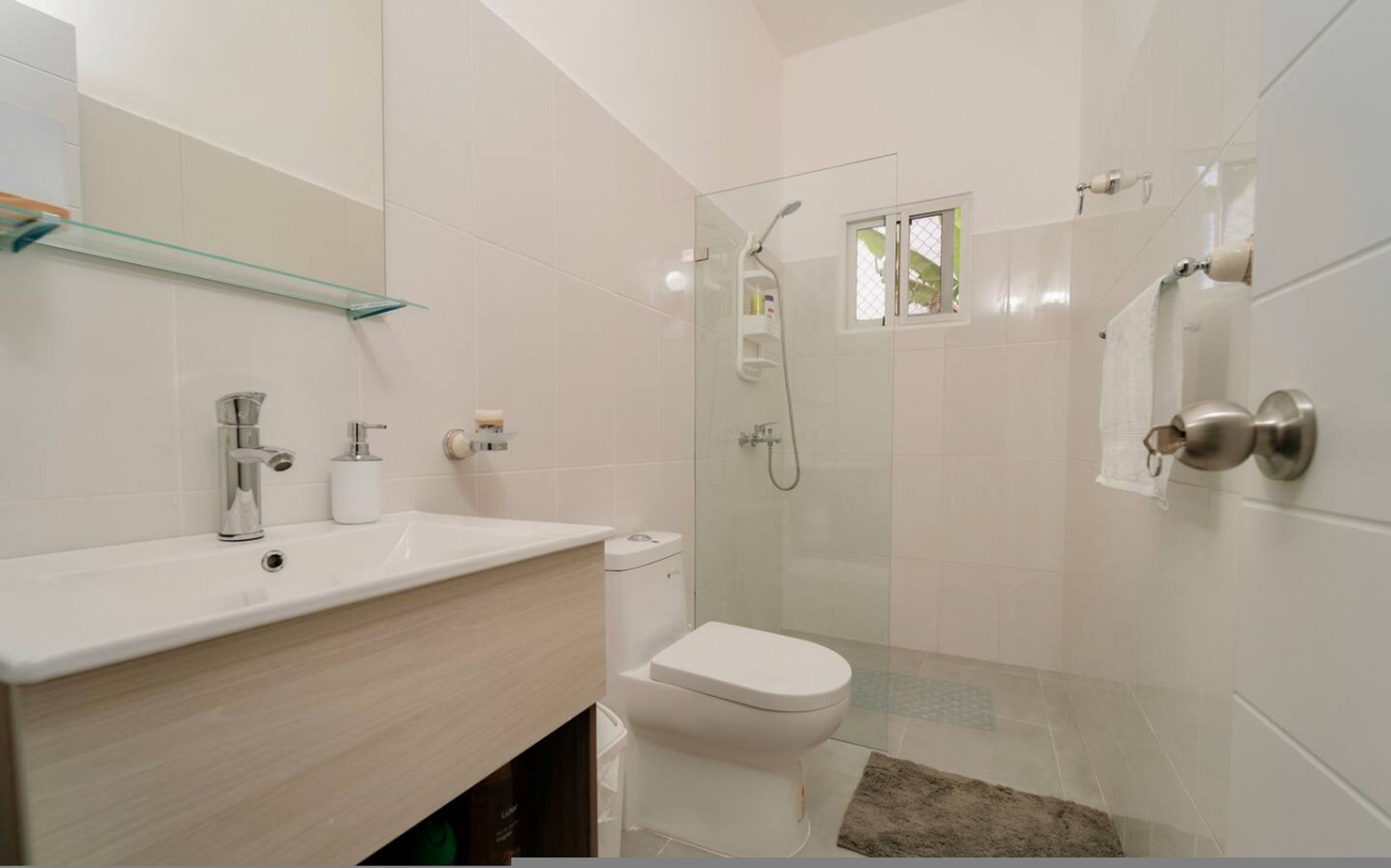 A modern bathroom with a glass shower enclosure, a white toilet, and a vanity with a mirror.