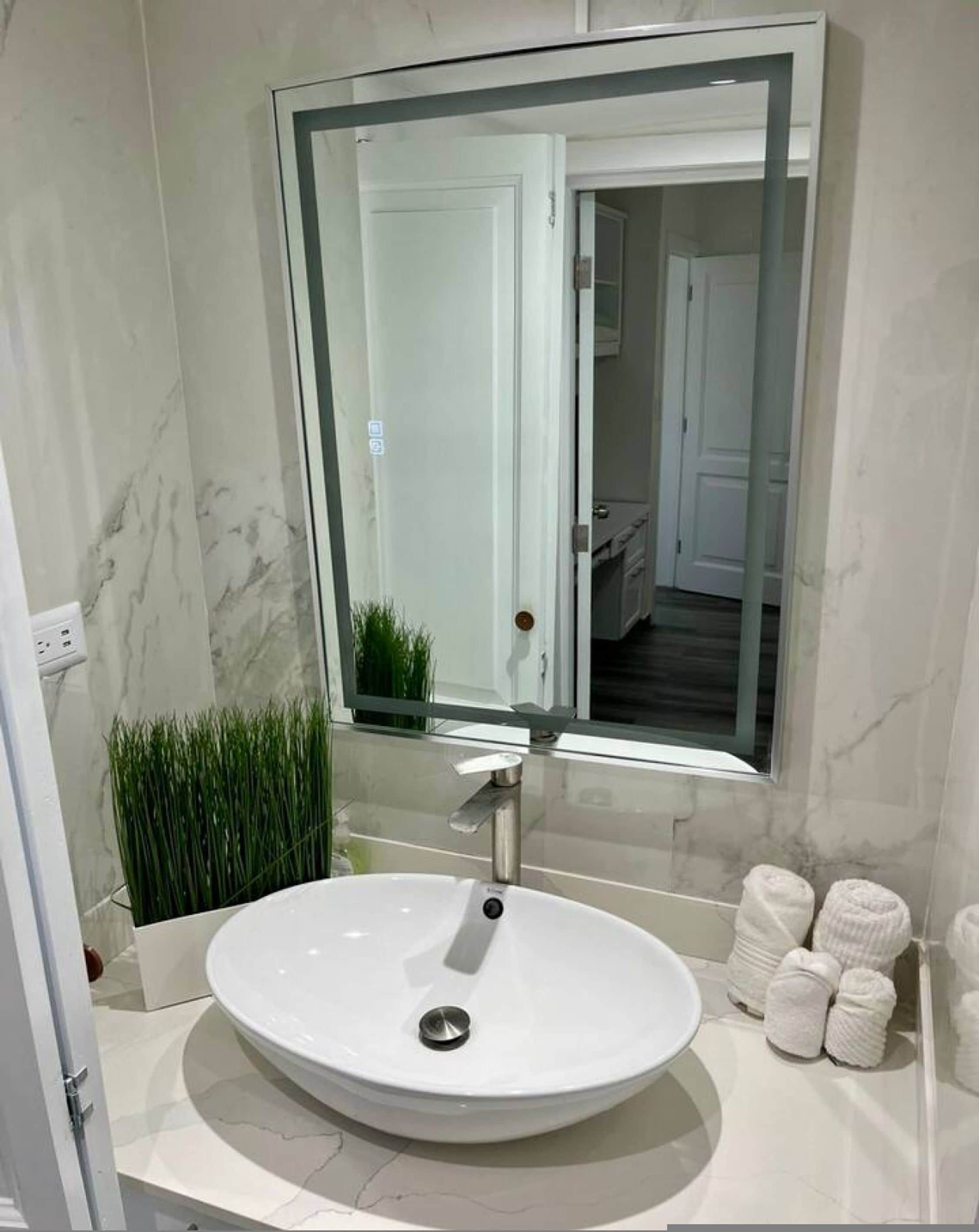 Un baño con un lavabo de mármol blanco, un espejo grande y una puerta que da a otra habitación.