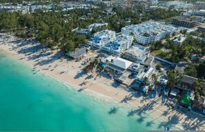 Vista aérea de una zona costera con playa, edificios y palmeras.