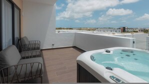 A balcony with a hot tub, a sofa, and a view of the cityscape. - 2BR Love Nest Jacuzzi Gym 1 Free Excursion (Punta Cana)