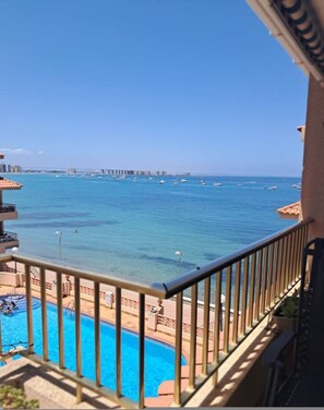 Un balcon avec une piscine et une vue sur la mer et les bâtiments situés au loin.