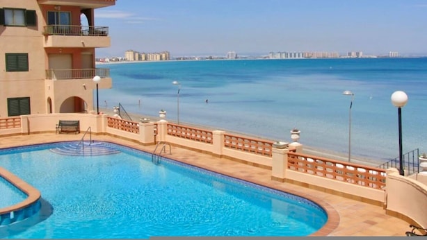 A swimming pool with a view of the sea and distant buildings. - Beachfront 3BR Condo w Pool Views Sleeps 10 (San Javier)
