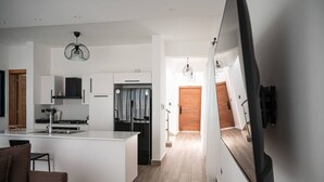 Una cocina moderna con armarios blancos, una isla central, una estufa integrada y un refrigerador negro.