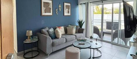 A modern living room with a blue accent wall, a grey sofa, a round coffee table, and a ceiling fan.
