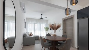 Ein moderner Wohnraum mit Essbereich, einer Sofagarnitur, einem Deckenventilator und einem großen Spiegel.