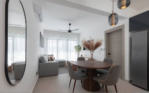 A modern living space with a dining area, a sofa set, a ceiling fan, and a large mirror. - Rooftop Jacuzzi Condo Free Airport Transfer (Punta Cana)