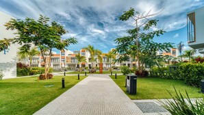 A pathway leading to a modern building with a tiled walkway, surrounded by greenery and palm trees. - 2-level Retreat Jacuzzi Free Airport Transfer (Punta Cana)
